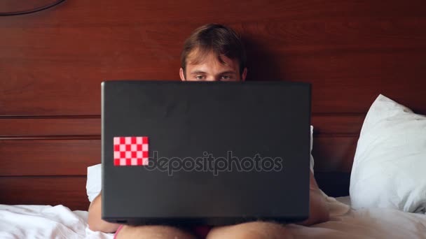 Sexy kobieta stara się uwieść człowiek działa na laptopie w łóżku. Dziewczyna zdejmuje swoją bieliznę przed chłopakiem, a on ignoruje jej, działa na laptopie. 4k, zwolnionym tempie — Wideo stockowe