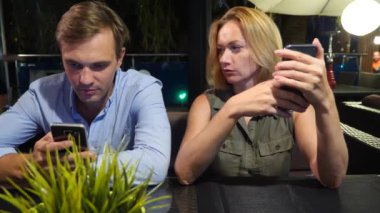 açık bir kafe aşık çift. Bir tarihte güzel kadın ve erkek. Herkes onun cep telefonu, 4 k bakıyor,