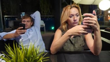 açık bir kafe aşık çift. Bir tarihte güzel kadın ve erkek. Herkes onun cep telefonu, 4 k bakıyor,