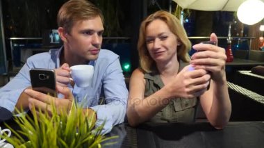 açık bir kafe aşık çift. Bir tarihte güzel kadın ve erkek. Herkes onun cep telefonu, 4 k bakıyor,