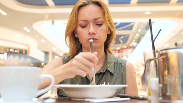 Donna esausta dalla dieta, mangiare insalata di cavolo in un caffè. 4k, rallenta. copia spazio — Video Stock