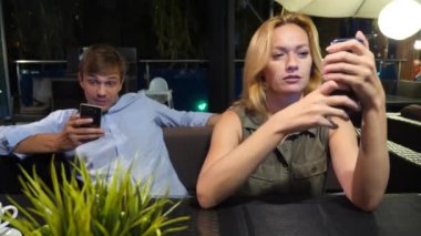 açık bir kafe aşık çift. Bir tarihte güzel kadın ve erkek. Herkes onun cep telefonu, 4 k bakıyor,