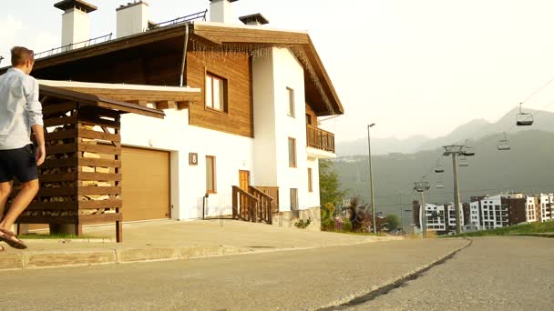 Business man on a background of a chalet, a house in the mountains. 4k. enjoys the view of nature — Stock Video