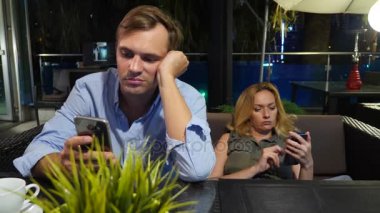 açık bir kafe aşık çift. Bir tarihte güzel kadın ve erkek. Herkes onun cep telefonu, 4 k bakıyor,