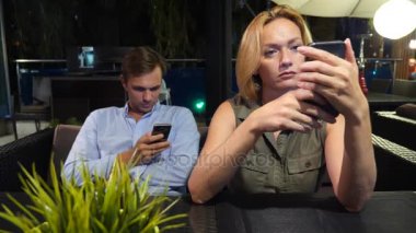 açık bir kafe aşık çift. Bir tarihte güzel kadın ve erkek. Herkes onun cep telefonu, 4 k bakıyor,