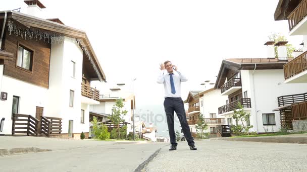 Uomo d'affari sullo sfondo di uno chalet, una casa in montagna. 4k. uomo amichevole parla per telefono — Video Stock