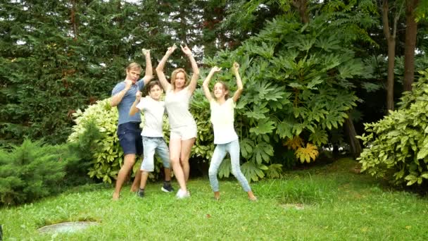 Lycklig familj dansar tillsammans på gräset i en park med vackra natur. 4 k. kopia utrymme. livsstil — Stockvideo