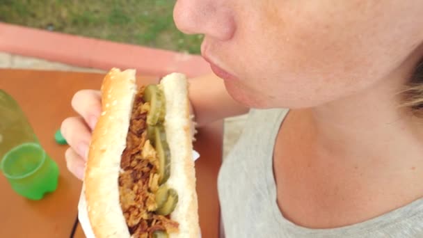 Приваблива дівчина їсть свіжий питний хліб з салатом зі свіжих овочів і м'яса, сидячи в кафе швидкого харчування під деревом в парку. 4K повільний рух — стокове відео