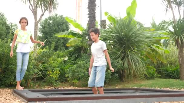 Bambini in pantaloncini che saltano su un trampolino. 4k. spazio per copiare, riprese al rallentatore — Video Stock