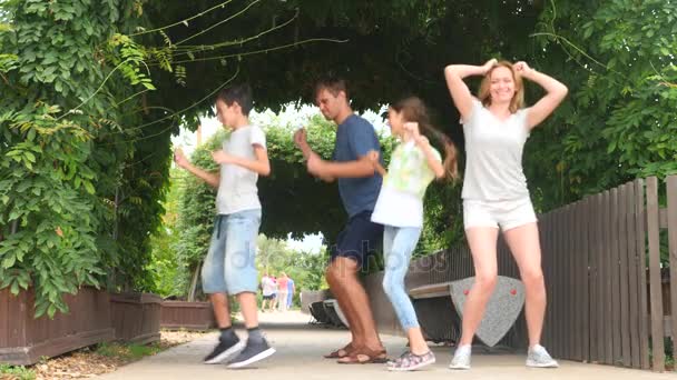 O familie fericită dansând împreună pe iarbă într-un parc cu o natură frumoasă. 4k. copia spațiu. stilul de viaţă. Slow motion — Videoclip de stoc