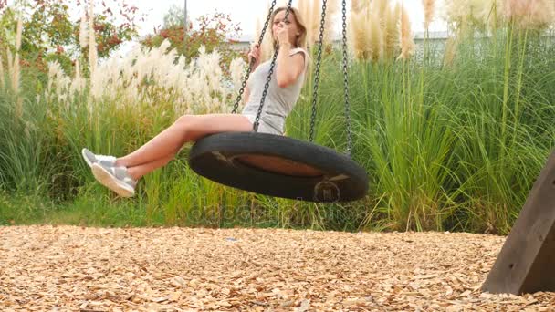 Romantique jeune femme balançant sur une balançoire sur le parc d'attractions de la ville. 4k, espace de copie. Mouvement lent . — Video