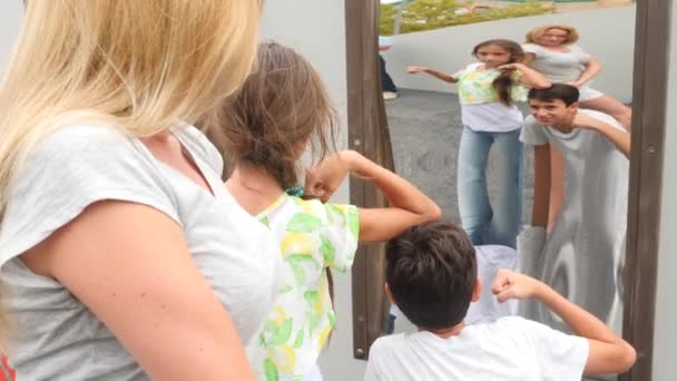 Moeder en haar kinderen, de tweeling jongen en de meisje neemt een reflectie in een valse mirror op de camera. levensstijl reis. ze lacht en gek. 4 k. Slowmotion — Stockvideo