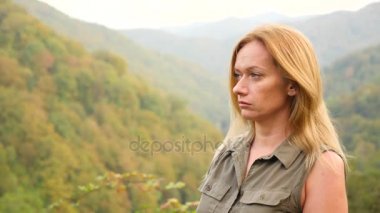 Kadar güzel genç kadın portre sarışın saç seyir Dağı'nda Rüzgar üfleme ile kapatın. Yavaş hareket 4k