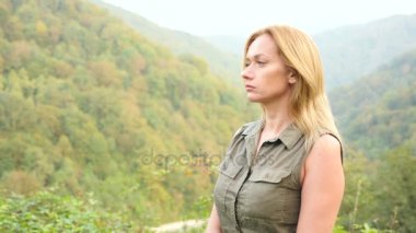 Kadar güzel genç kadın portre sarışın saç seyir Dağı'nda Rüzgar üfleme ile kapatın. Yavaş hareket 4k