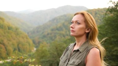 Kadar güzel genç kadın portre sarışın saç seyir Dağı'nda Rüzgar üfleme ile kapatın. Yavaş hareket 4k