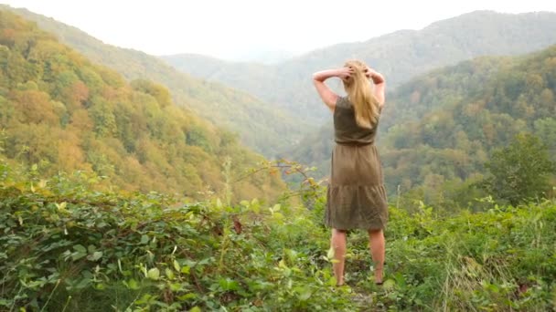 Крупный план портрета красивой молодой женщины с светлыми волосами, дующими на ветру и смотрящими на гору. Slow Motion 4k — стоковое видео