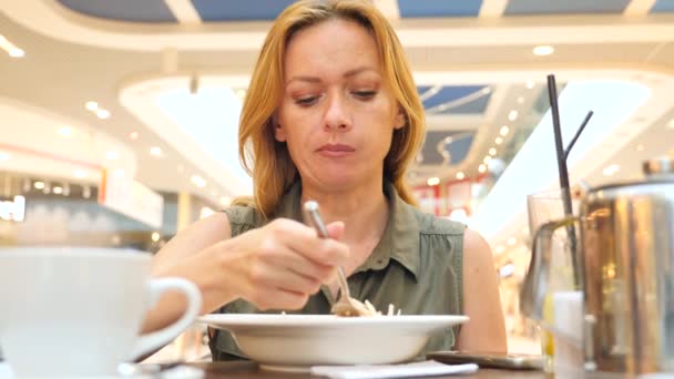 Donna esausta dalla dieta, mangiare insalata di cavolo in un caffè. 4k, rallenta. copia spazio — Video Stock