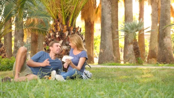 Pareja feliz comiendo hamburguesas. Al aire libre. snack comida rápida. 4k, cámara lenta — Vídeo de stock