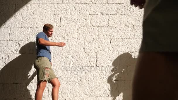 Szemtelen fickó, teremtő egy profi fotós ellen a fehér téglafal. 4k, lassú mozgás, space másolása — Stock videók