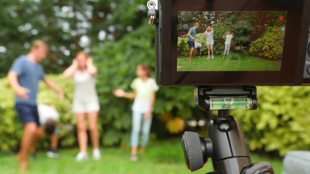 Registrare video di famiglia sulla videocamera. Famiglia felice che balla insieme sull'erba in un parco con una bella natura. 4k. copiare spazio. stile di vita. Rallentatore — Video Stock