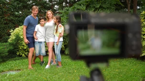 Record familie video op uw camcorder. Gelukkige familie samen dansen op het gras in een park met prachtige natuur. 4 k. kopie ruimte. leefstijl. Slow motion — Stockvideo