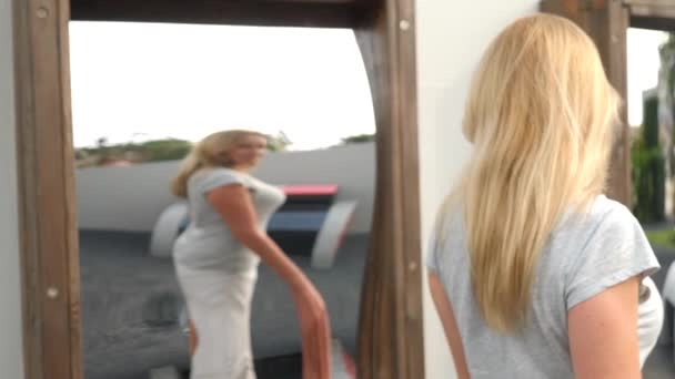 Una mujer toma su reflejo en un falso espejo en la cámara. viaje estilo de vida. se ríe y tonta. 4k. Movimiento lento — Vídeos de Stock
