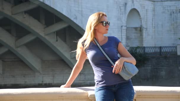 Hermosa joven en el fondo del puente sobre el río. 4k, grabación en cámara lenta, espacio para copiar . — Vídeos de Stock