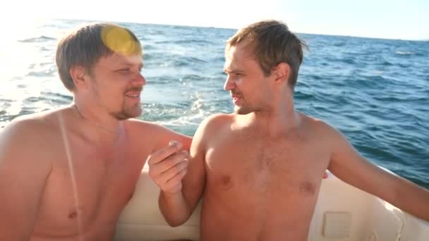 Dos amigos alegres están flotando en un yate en el mar, se abrazan y sonríen. 4k, cámara lenta — Vídeos de Stock