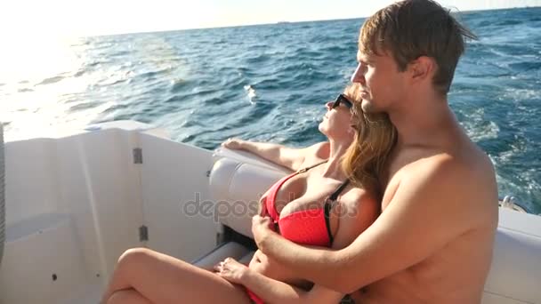 Счастливая любящая пара смотрит в сторону, сидя вместе на яхте. 4k, slow motion — стоковое видео