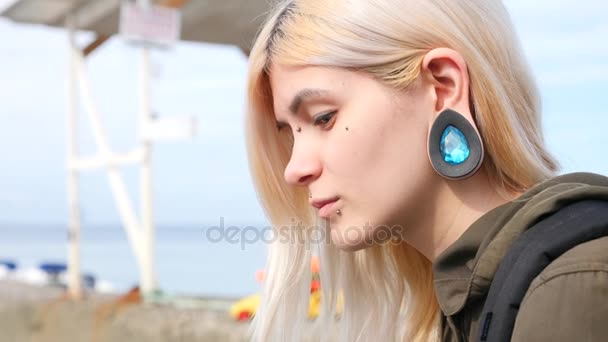 Modificação corporal, retrato de uma menina com piercings faciais e túneis nas orelhas. 4k, tiro em câmera lenta, espaço de cópia — Vídeo de Stock