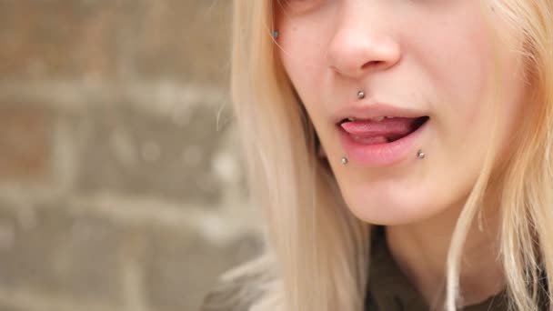 Modification corporelle, portrait d'une fille avec des piercings du visage et des tunnels dans les oreilles. une fille avec une langue fendue. montre la langue. 4k, prise de vue au ralenti, espace de copie — Video