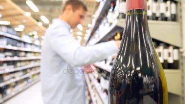 genç bir romantik adam şarap romantik bir akşam yemeği için seçer. alkol satın alma. 4k, ağır çekim, görüntü