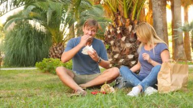 Mutlu çift hamburger yeme. Açık havada. Fast food snack. 4k, ağır çekim