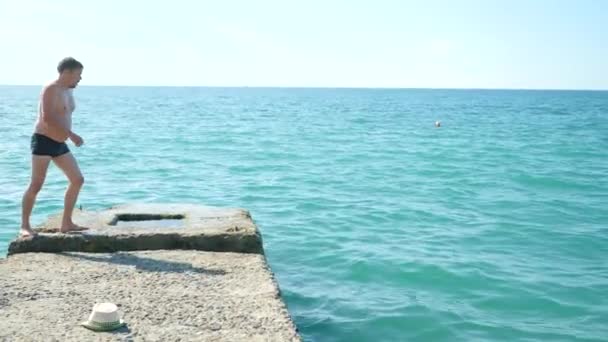 El hombre se sumerge en el muelle en el mar. 4k, cámara lenta — Vídeo de stock