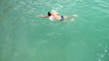 adam denizde yüzüyor. Yukarıdan görüntüleyin. 4k, ağır çekim