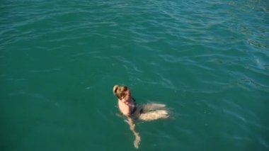 Sarışın güzel kadının açık deniz, suda yüzen. Yukarıdan görüntüleyin. Ağır çekim.