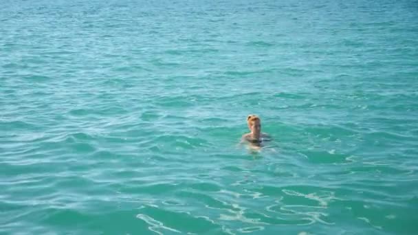 Mujer guapa rubia disfrutando del agua en el mar abierto, flotando. Vista desde arriba. Movimiento lento . — Vídeos de Stock