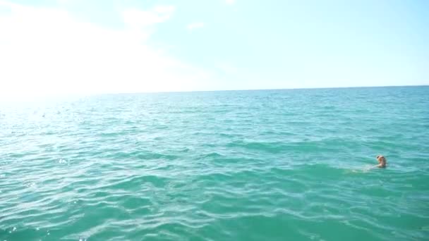 公開した海で水を楽しむ金髪のきれいな女性浮動。上からの眺め。スローモーション. — ストック動画