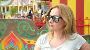 Mutlu kadın Lunaparktaki bir bankta oturuyordu. 4 k yavaş hareket. kopya alanı. yaşam tarzı.