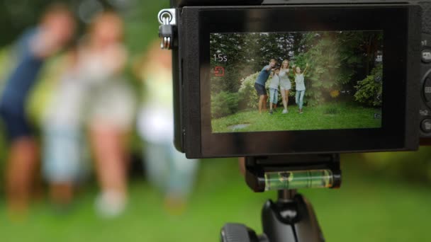 Nahrávat video na kameru rodina. Šťastná rodina tančí spolu na trávě v parku s krásnou přírodou. 4 k. kopie prostor. životní styl. Zpomalený pohyb — Stock video