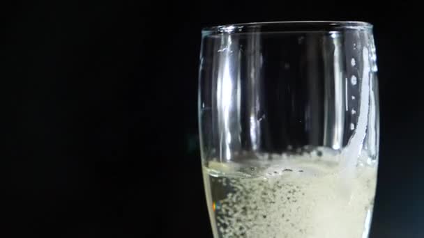 Gros plan, champagne moussant dans un verre sur fond noir. au ralenti — Video