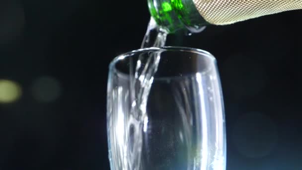 Крупный план, пенящееся шампанское в стакане на черном фоне. 4k, slow motion — стоковое видео