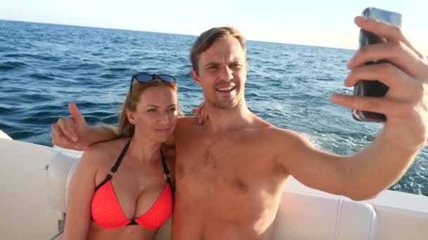 Joyeux couple amoureux, assis ensemble sur un yacht, prenant des selfies sur son smartphone. 4k, au ralenti — Video