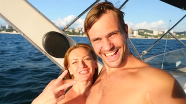 Happy älskande par, sitter tillsammans på yacht, tar selfies på sin smartphone. 4k, Slowmotion — Stockvideo