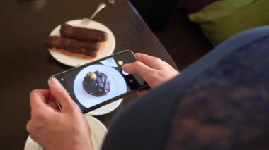 kadın fotoğraf üstünde onların smartphone sosyal ağlarda düzenlemeniz için bir kafede lezzetli güzel tatlılar eller. 4k, yavaş çekim