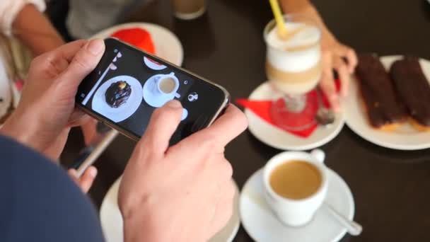 Жіночі руки фотографії смачні красиві десерти на своєму смартфоні в кафе, щоб викласти в соціальних мережах. 4k, повільна стрільба — стокове відео