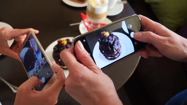 Mulheres mãos fotografia deliciosas sobremesas bonitas em seu smartphone em um café para colocar em redes sociais. 4k, tiro em câmera lenta — Vídeo de Stock