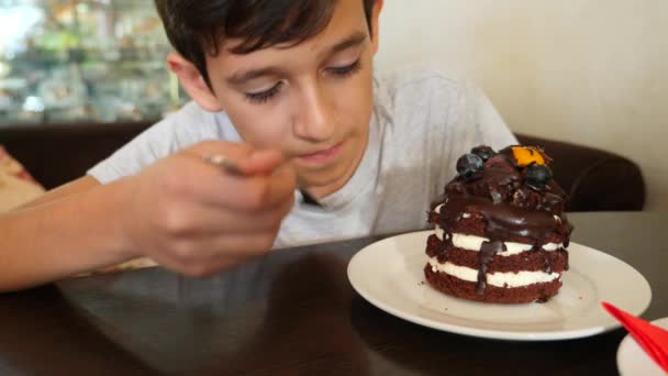 The boy in glasses is eating a delicious dessert in a cafe. 4k slow motion — Stock Video