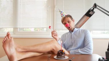 Yalnız bir adam bir tatil kutluyor, o tek başına bir kek ve bir mum ile bir masada oturuyor.