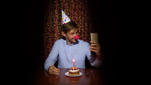 En ensam man firar semester, han sitter ensam vid ett bord med en tårta och ett ljus. 4k, Slowmotion — Stockvideo